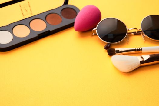 Eyeshadow makeup brushes soft sponge glasses yellow background. High quality photo