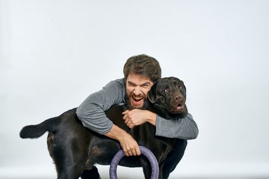 Man with dog training gray ring doing exercises pets light background. High quality photo