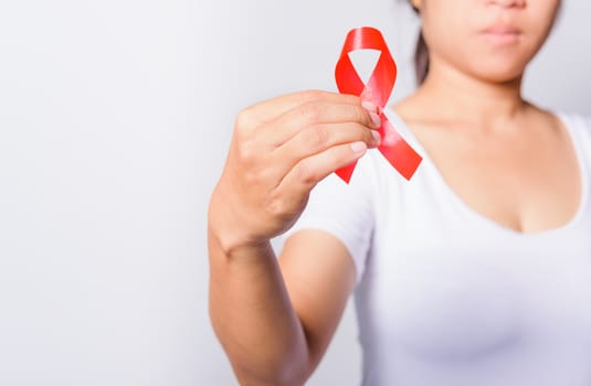 Closeup of female with red ribbon HIV AIDS on hand, World AIDS Day and medicine concept