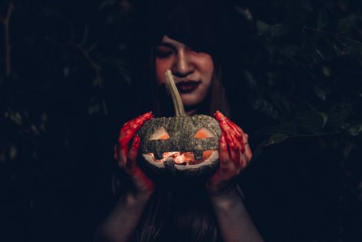 Portrait of woman ghost horror her have pumpkin on hand in forest, halloween day concept