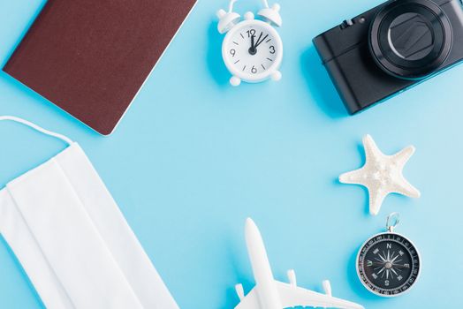 World Tourism Day, Top view of minimal model plane, airplane, starfish, compass, smartphone blank screen and face mask isolated on blue background, accessory flight holiday under coronavirus concept