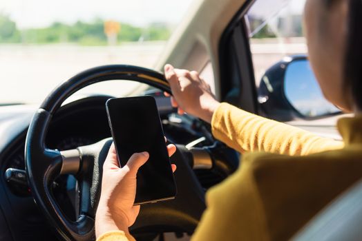 Asian woman inside a car and using a hand holding mobile smartphone blank screen while driving the car in the morning during going to work on highway, Transportation and vehicle concept