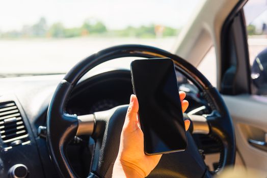 Asian woman inside a car and using a hand holding mobile smartphone blank screen while driving the car in the morning during going to work on highway, Transportation and vehicle concept