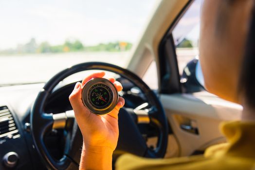 Asian woman inside a car and using compass to navigate while driving the car she find navigation location to go, Transportation and vehicle concept