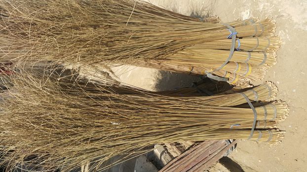 Bunch of brown colored straw broom. Old style broom used for housekeeping in rural area in Asian countries.