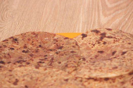 Traditional paratha - Macro closeup with selective focus of homemade oily bread or parotta on a plate on wooden floor. Chapati is traditional food of southeast Asia.