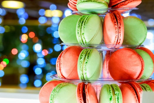 French colorful macarons tower Multicolor macaroon on christmas bokeh light abstract holiday background Sweets. Food background.