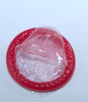 Red condom isolated on white background, sexually transmitted infection prevention concept and contraception.