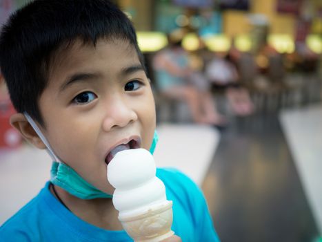 A boy eating ice cream inside a mall with a blurred background