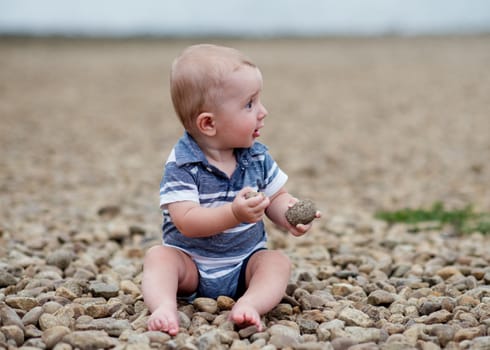 Small boy playng with stones on the seaside