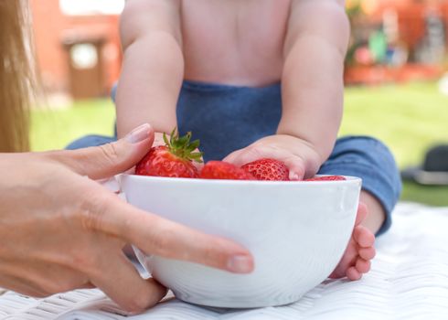 a child grabbing strawberries from a bowl