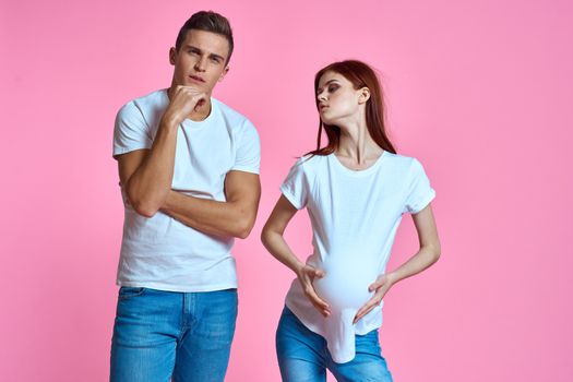 pregnant mom and happy father on pink background Young family waiting for baby. High quality photo