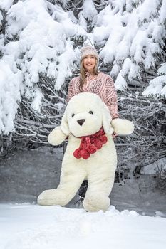 Smiling happy woman out in the snow with a large soft toy