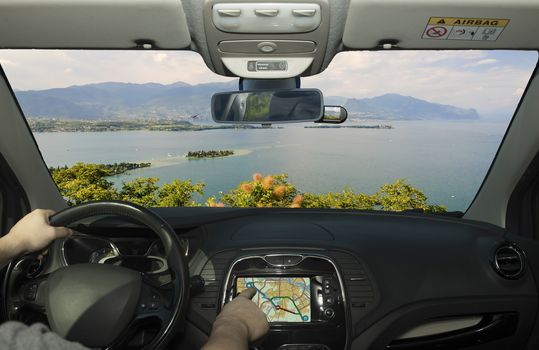 Driving a car while using the touch screen of a GPS navigation system towards Lake Garda, Italy
