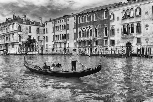 Unidentified people on a traditional Gondola with scenic architecture along the Grand Canal in Cannaregio district of Venice, Italy