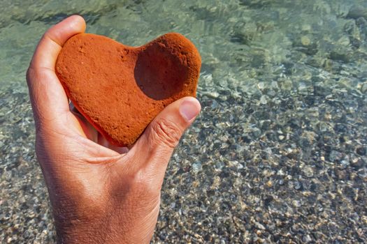 orange heart shaped stone at the beach