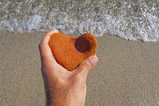 orange heart shaped stone at the beach