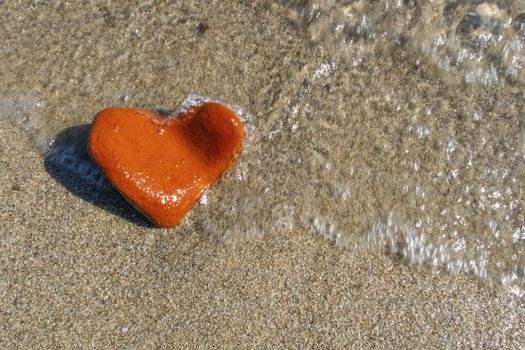 orange heart shaped stone at the beach