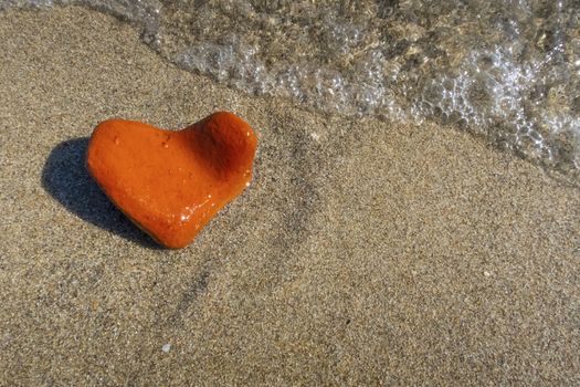 orange heart shaped stone at the beach