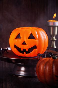 Close up of spooky Halloween tricks, concept of horror festival decor, pumpkin lantern with candlestick and smoke.