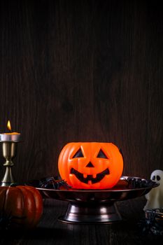 Close up of spooky Halloween tricks, concept of horror festival decor, pumpkin lantern with candlestick and smoke.