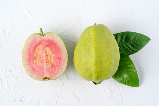 Top view, flat lay of delicious beautiful Red guava with fresh green leaves isolated on white table background, studio overhead table shot with copy space.