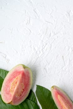Top view, flat lay of delicious beautiful Red guava with fresh green leaves isolated on white table background, studio overhead table shot with copy space.