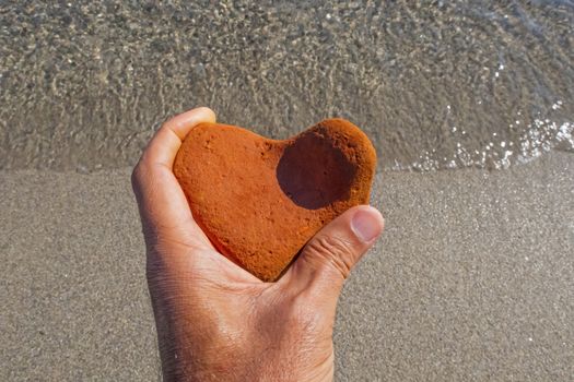 orange heart shaped stone at the beach