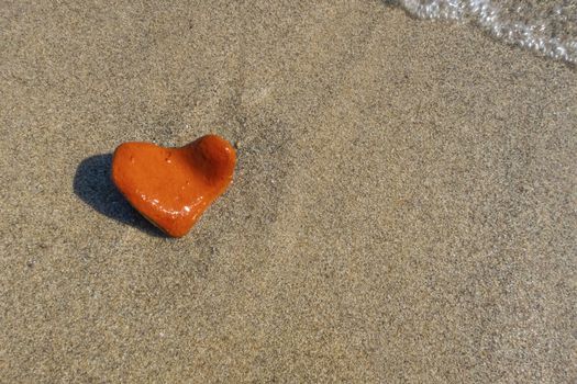 orange heart shaped stone at the beach