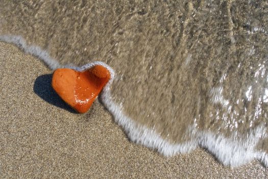 orange heart shaped stone at the beach