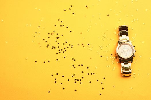 Wristwatch on yellow background and Copy Space glitter. High quality photo