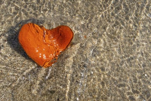 orange heart shaped stone at the beach