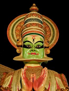 Close up image of porcelain idol face of Kerala Kathakali performer with clear black background.