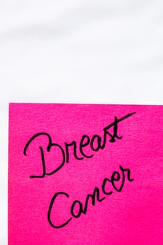 Breast cancer handwriting text close up isolated on pink paper with copy space. Writing text on memo post reminder