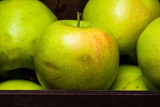 Ripe green apples in a wooden crate, close up isolated.