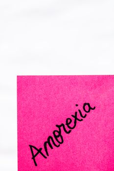 Anorexia handwriting text close up isolated on pink paper with copy space. Writing text on memo post reminder