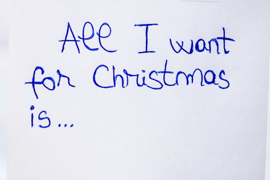 All I want for Christmas handwriting text close up isolated on white paper with copy space. Writing text on memo post reminder