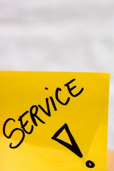 Service handwriting text close up isolated on yellow paper with copy space.