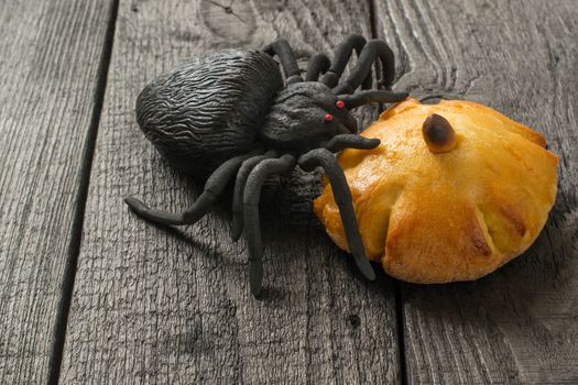 Homemade sweet pumpkin buns. Original baking in form of pumpkin and black toy spider. Symbols Halloween. Idea of design meal for Halloween party. Scary and funny Halloween food 