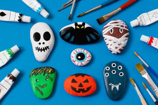 Drawing on stones Halloween characters. Art project for children. DIY concept. Halloween party decor. Skull, bat, mummy, stuffed animal, eye, pumpkin, monster painted on sea stones