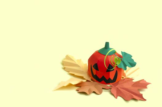 Volumetric paper Jack-o-lantern with autumn leaves on yellow background. Paper art and craft. Festive Halloween concept. Copy space