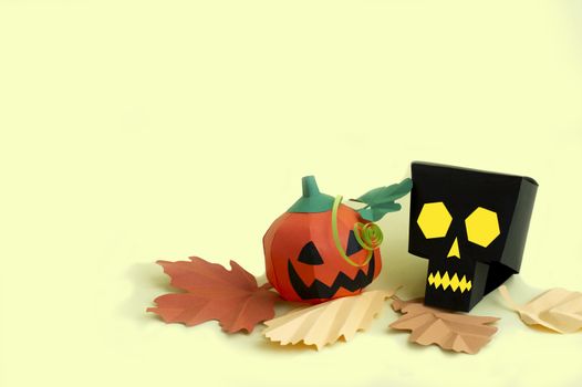 Volumetric paper skull and Jack-o-lantern with autumn leaves on yellow background. Paper art and craft. Festive Halloween concept. Copy space