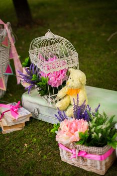 street decorations for a children's party. Retro suitcase with flowers with a teddy bear in a green park. Party on the street.