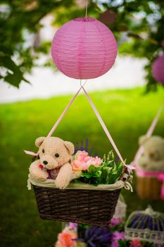 street decorations for a children's party. A basket with a teddy bear in a air balloon in a green park.