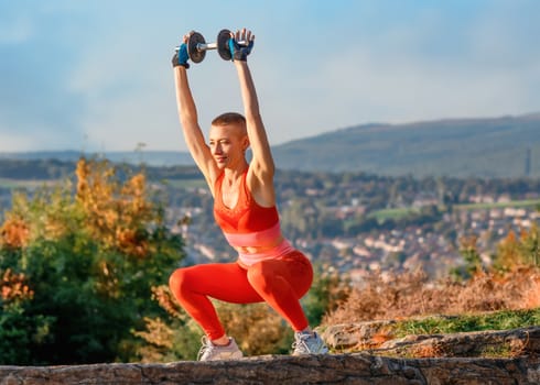 woman doing dumbbell exercises in the park against city
