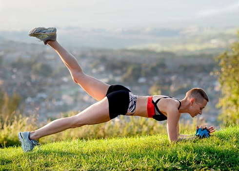 woman exercising outdoors on the grass against cityty