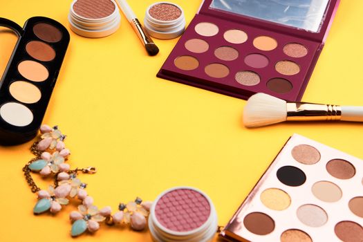 Professional eyeshadows and makeup brushes on a yellow background make-up decoration. High quality photo