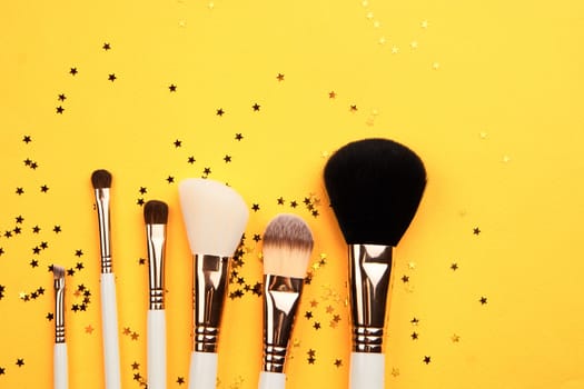 makeup brushes of different sizes on yellow background cropped view Copy Space. High quality photo