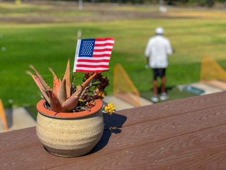 Patriotic flower pot with American flags and golfer on the background. American flag decoration.