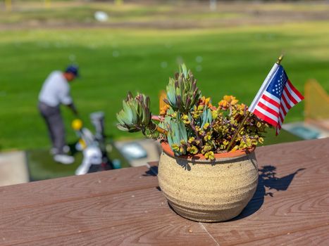 Patriotic flower pot with American flags and golfer on the background. American flag decoration.